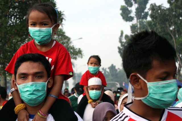 Warga Pekanbaru, Riau, memakai masker saat berolahraga di pagi hari. Kabut asap di Pekanbaru makin hari makin pekat. Foto oleh Azwar/EPA 