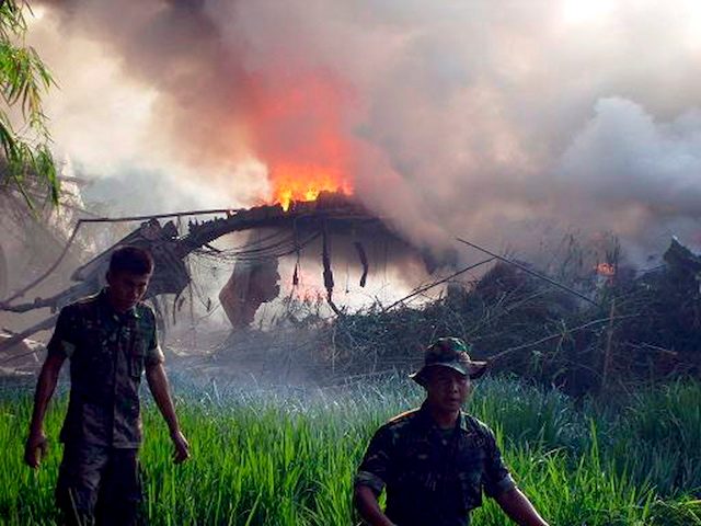 Dua orang tentara berjalan di samping pesawat Hercules C-130 yang terbakar di Magetan, Jawa Timur, 20 Mei 2009. Foto dari Soegeng Haryanto/EPA 