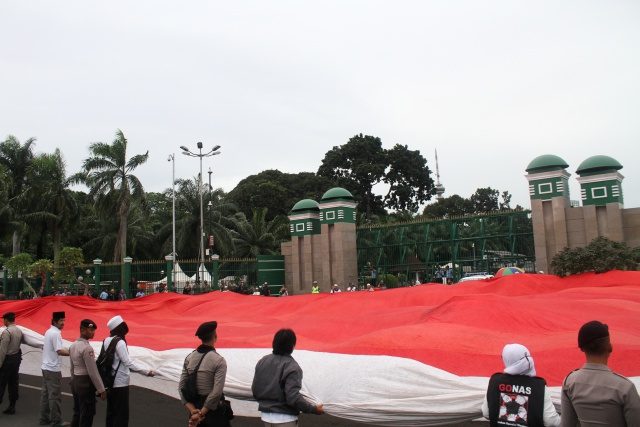 BENDERA. Umat muslim membentangkan bendera merah putih, besar saat melakukan aksi damai di Gerbang Komplek Parlemen Senayan, Jakarta, Jumat, 2 Desember. Foto oleh Risky Andrianto/ANTARA 