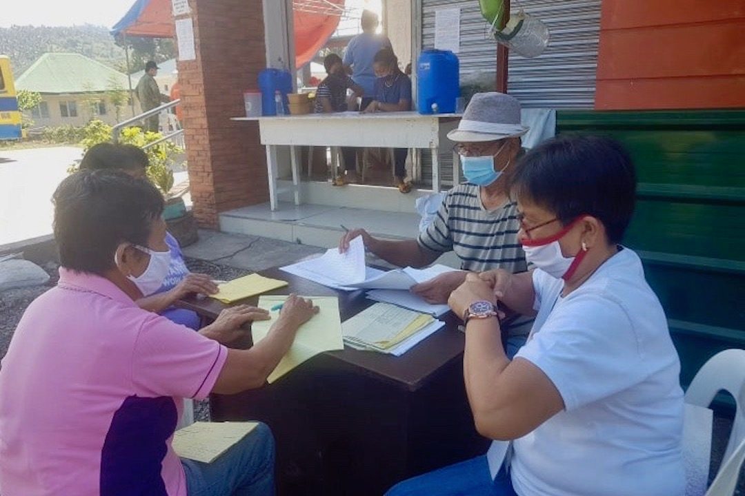 WORK OUTSIDE. Barangay officials of Buluang, Baao, Camarines Sur work outside to validate paperwork for their social relief efforts. Photo from Alan Bolo 
