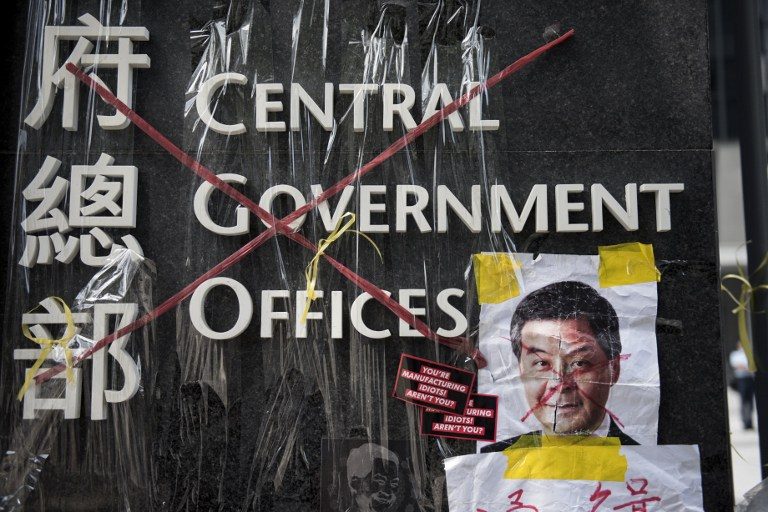 The sign for the Hong Kong central government offices is seen crossed out with red tape by democracy activists, next to a defaced image of Hong Kong's Chief Executive Leung Chun-ying on September 28, 2014. Alex Ogle/AFP