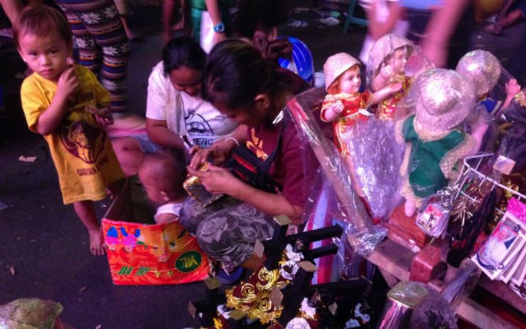 FOR THE KIDS. Daisy Cruz (maroon) packs Nazareno statues while her son (L) eats his dinner. 