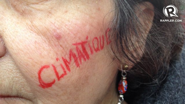 CLIMATE. A woman paints powerful words over her face as she joins thousands of other advocates out in the streets. 