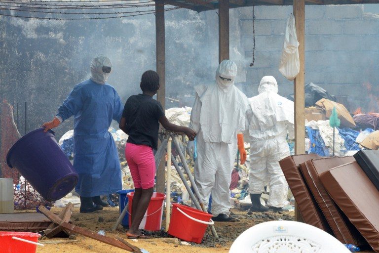 BIOHAZARD. Health care workers wearing full body suits burn infected items at the John Fitzgerald Kennedy hospital of Monrovia on September 3, 2014. Dominique Faget/AFP