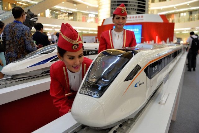 This photo taken on August 13, 2015 shows Indonesian models with scale models of Chinese-made bullet trains on exhibition at a shopping mall in Jakarta. Bay Ismoyo/AFP 