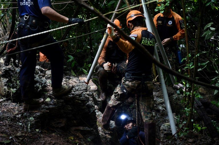 RESCUE. Thai rescue specialists (in orange) help a Thai Airforce soldier descent into a possible opening to the Tham Luang cave, at the Khun Nam Nang Non Forest Park in Chiang Rai province on June 30, 2018 as the rescue operation continues for the children of a football team and their coach. Photo by Lillian Suwanrumpha/AFP 