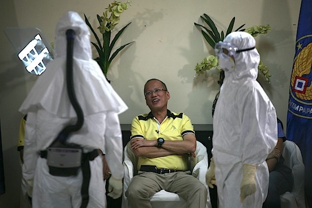 FIGHTING EBOLA. President Benigno Aquino III intently watches how to use a protective gear against Ebola virus during a press briefing at Villamor Airbase in Pasay City on  November 7, 2014 after his Guiuan visit. Photo by Jose Del/Rappler