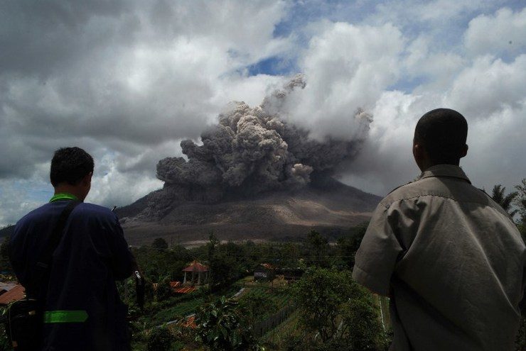 FRESH ERUPTION. Residents watch as dark giant ash clouds rise from the crater of Mount Sinabung volcano during an eruption on October 8, 2014, as seen from Karo district in North Sumatra. Photo by AFP