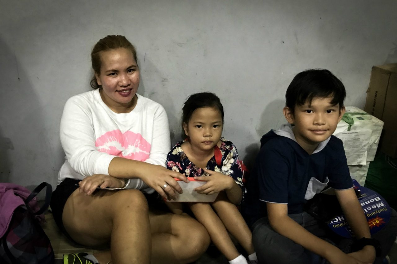 FAMILY. Cathy Legaspi and her two kids wait by the side of JAC Liner terminal, away from the crowd, as her husband lines up for them.  