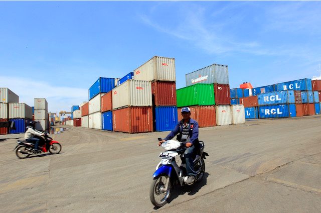 Seorang pengendara motor melintas di depan tumpukan kontainer di Jakarta International Container Terminal (JICT), Pelabuhan Tanjung Priok, November 2012. Foto oleh Bagus Indahono/EPA 