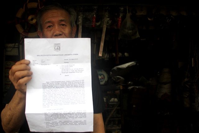 Seorang pedagang menunjukkan surat peringatan pertama (SP1) dari pemerintah provinsi DKI Jakarta di kawasan Pasar Ikan, Luar Batang, Penjaringan, Jakarta, Kamis, 31 Maret. Foto oleh Yossy/ANTARA 
