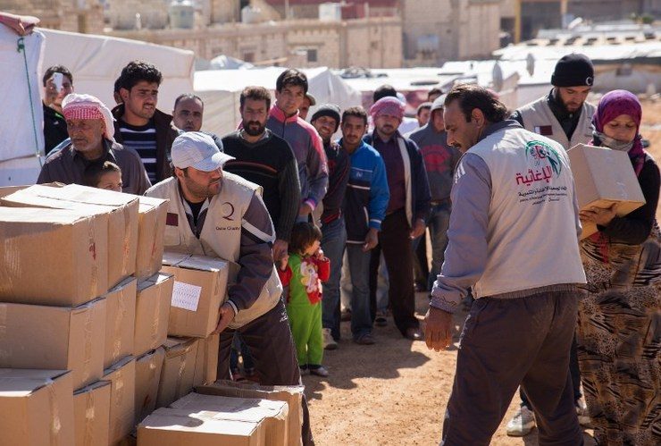 Volunteers from two of three non-governmental organizations currently operating relief groups in Arsal, Lebanon, after international humanitarian actors halted operations in the border town due to security reasons, distributes boxes of aid to Syrian refugees in Al-Masri refugee camp on October 25, 2014. Maya Hautefueille/AFP