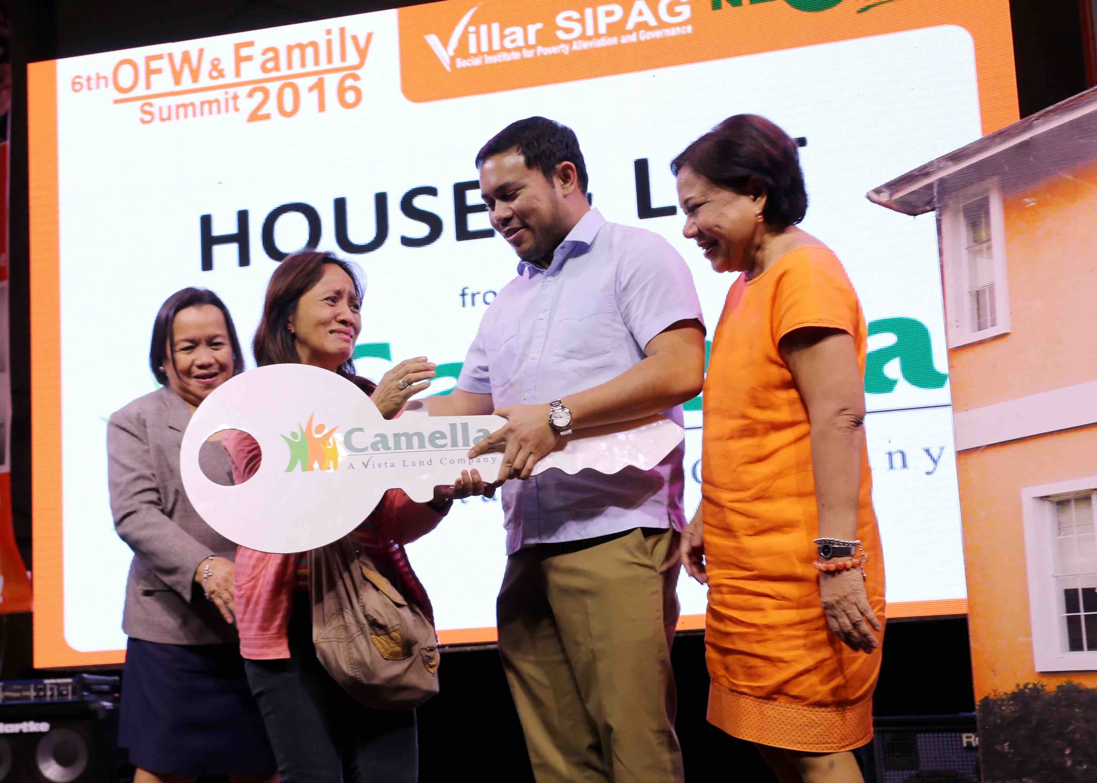 HOUSE AND LOT. Senator Villar and son DPWH Secretary Mark Villar hand over the ceremonial key to a lucky OFW after winning a new house and lot from Camella Homes during Villar SIPAG’s 6th OFW and Family Summit in Manila. Photo from Villar's office  
