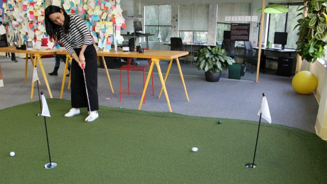 Kristine Reyes-Lopez of Messy Bessy gets a try at golf putting in one of the common areas during their tour of Google HQ. 