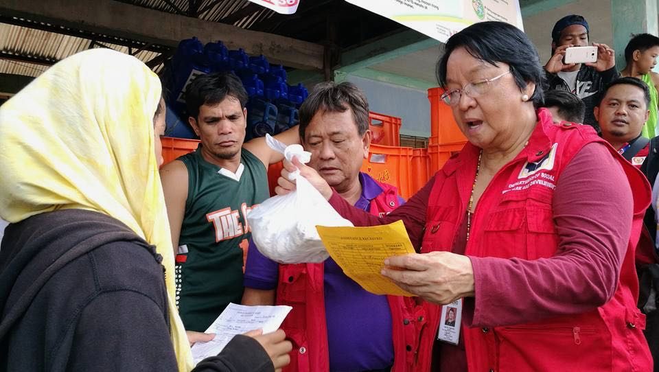 VETTING BENFICIARIES. Secretary Judy Taguiwalo checks a list before handng out a bag of goods to a Marawi City. Photo from DSWD    