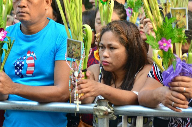 SACRED RITUAL. A woman has her palm fronds (palaspas) blessed outside Baclaran Church on Palm Sunday, March 25, 2018. Photo by Angie de Silva/Rappler  