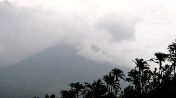 CHARMING LADY. Mayon Volcano hides beneath a veil of rain clouds