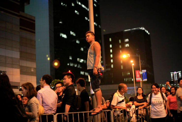 CIVIL DISOBEDIENCE. A pro-democracy protester stands on a barrier as he looks at anti-occupy protesters trying to move into the occupied area during ongoing protests of mass civil disobedience campaign Occupy Hong Kong outside the government offices in Admiralty, Hong Kong, China, 07 October 2014. Mast Irham/EPA