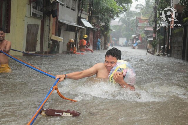 QC FLOOD. A man holds on to a rope put in place by rescuers at Barangay Holy Spirit in Quezon City on September 19, 2014. Photo by Joel Leporada/Rappler