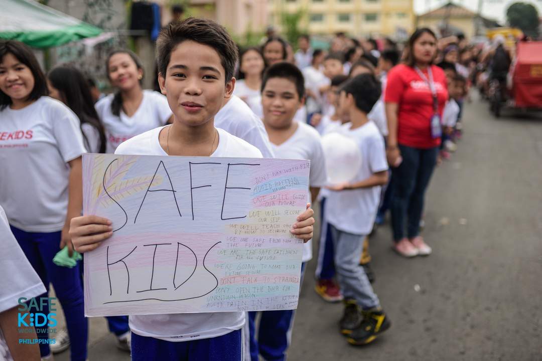 PARADE. An elementary student holds a sign that lists the things children must do and avoid to remain safe. Photo by Heinz Reimann Orais  