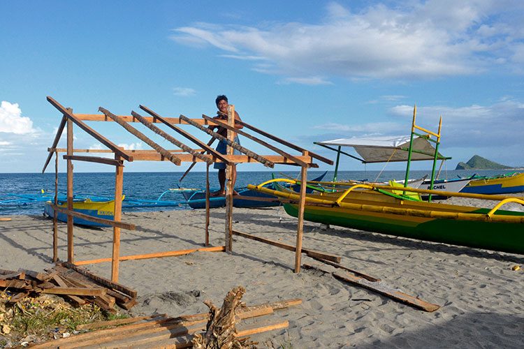 NO DWELL ZONES. A Tanauan local in Barangay San Jose builds temporary shelter along the coast. Photo by Leanne Jazul/Rappler