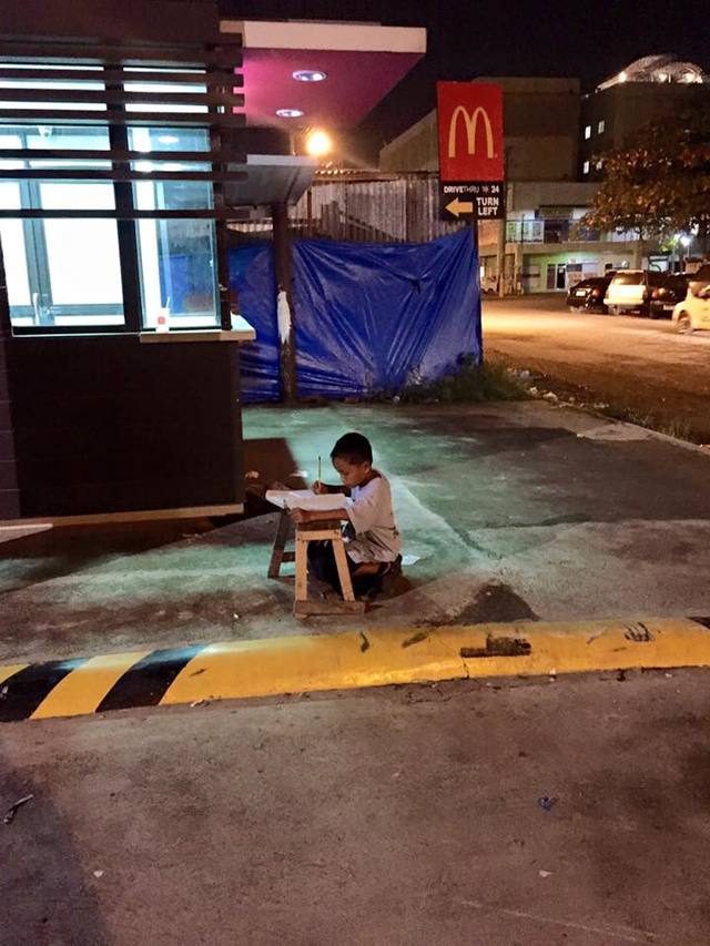 HARDWORKER. Daniel studies on one of Cebu's sidewalks to keep up with his schoolwork because his family has no electricity at home. Photo from Joyec Torrefranca's Facebook account 