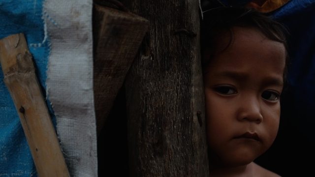 ONE YEAR AFTER. An internally displaced child looks out from a makeshift home at the Enriquez Sports Complex in Zamboanga City. Photo by Patricia Evangelista / Rappler