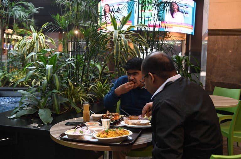 RICH DELHI. This photograph taken on February 6, 2019 shows visitors eating at The Walk food courtyard, a space designed with green spaces and artificial water bodies to help filter out unhealthy air pollution, in New Delhi. Photo by Sajjad Hussain/AFP  