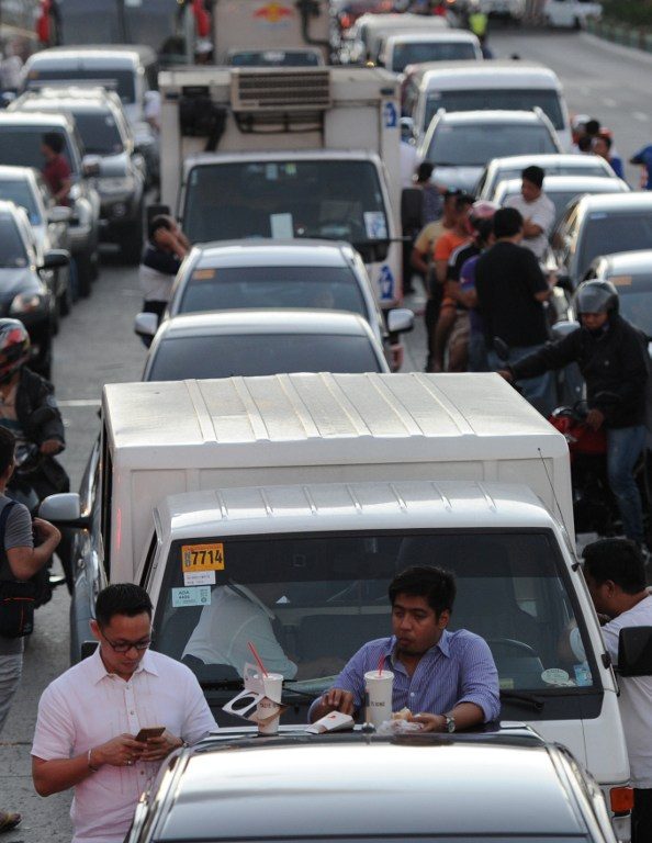 MANILA GRIDLOCK. Motorists eat a meal on the back of their vehicles after being caught in traffic during the APEC summit in Manila in November 2015. The Philippines needs to improve infrastructure and requires funding from AIIB. File photo by Ted Aljibe/AFP 
