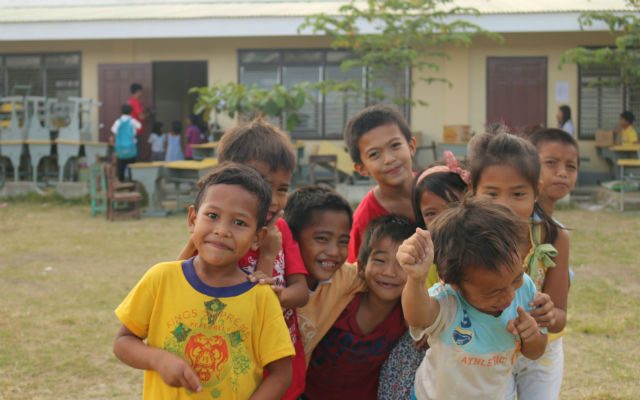Jhon Rick (yellow shirt) poses with his friends in front of Botongan Elementary School. Photo from World Vision   