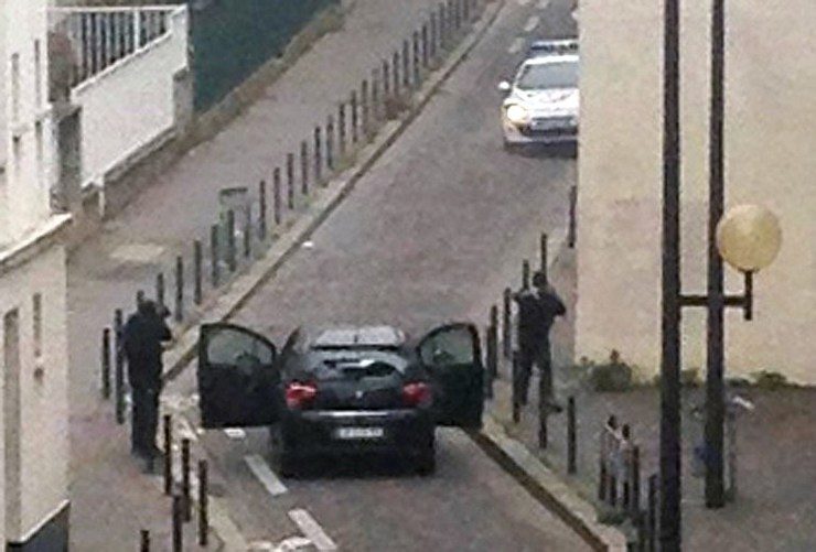 Armed gunmen face police officers near the offices of the French satirical newspaper Charlie Hebdo in Paris on January 7, 2015, during an attack on the offices of the newspaper which left eleven dead, including two police officers, according to sources close to the investigation. Anne Gelbard/AFP