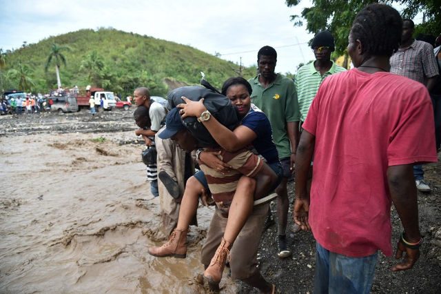 Haitian people cross the river La Digue in Petit Goave where the bridge collapsed during the rains from Hurricane Matthew, southwest of Port-au-Prince, October 6, 2016. Photo by Hector Retamal/AFP 