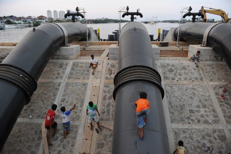 FLOOD CONTROL. Children play on giant pipes of a flood control station built along a dike protecting the community from sea water intrusions in Jakarta. The Indonesian capital is constructing a sea wall in the northern coastal district. Photo by Romeo Gacad/AFP 