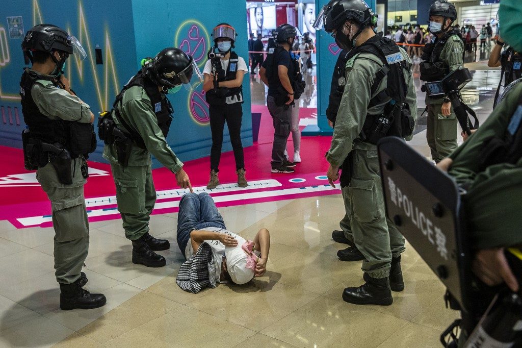 WHITE TERROR. A riot police officer points at a woman laying down after being searched during a demonstration in a mall in Hong Kong on July 6, 2020. Photo by Isaac Lawrence/AFP 