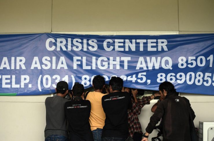 Kru media mencoba mengambil gambar salah satu keluarga penumpang AirAsia QZ8501 di Bandara Juanda, Surabaya. Foto oleh Manan Vatsyayana/AFP
