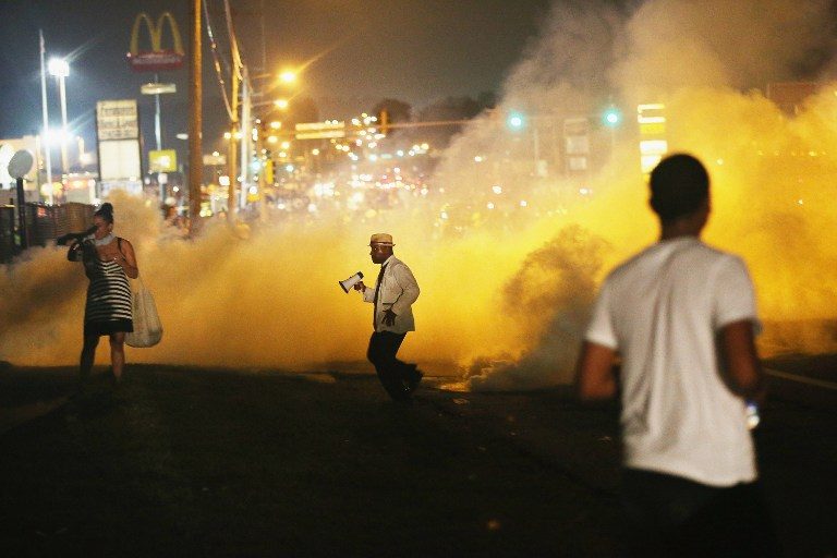 GASSED. People make their way through the haze as tears gas fills the street during a demonstration over the killing of teenager Michael Brown by a Ferguson police officer on August 17, 2014 in Ferguson, Missouri. Scott Olson/Getty Images/AFP