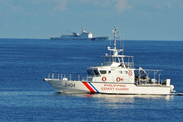 WEST PHILIPPINE SEA. A Philippine Coast Guard ship (R) sails past a Chinese Coast Guard ship during a joint search and rescue exercise between Philippine and US coast guards near Scarborough Shoal. Photo by Ted Aljibe/AFP 