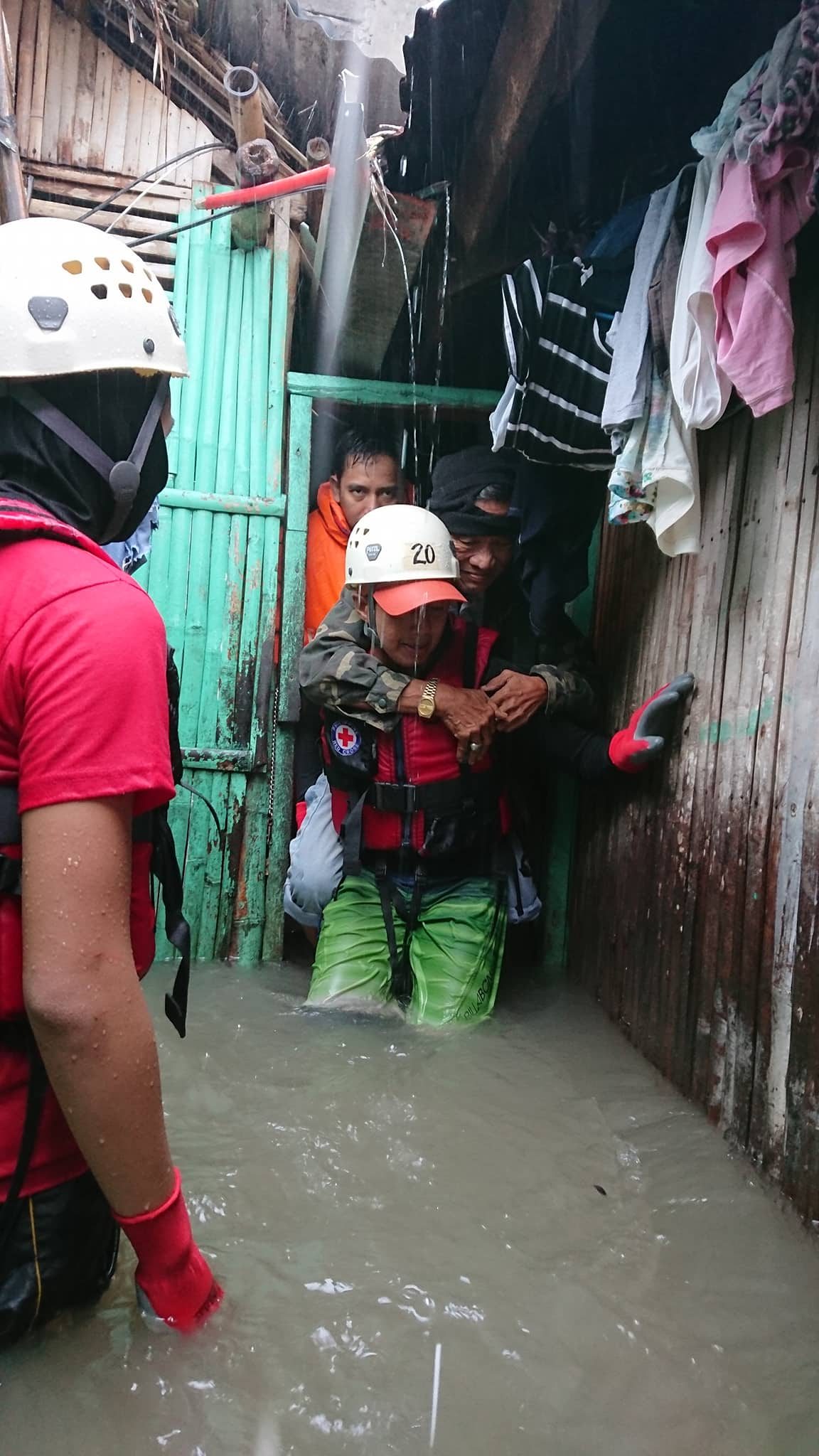 RESCUE. A disaster responder carries an old man amid a knee-level flood. Photo courtesy of Philippine Red Cross - Camarines Sur 