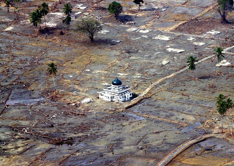 Masjid Baiturrahim bertahan di tengah sapuan gelombang tsunami yang melanda Meulaboh, Aceh, pada 26 Desember 2014 silam. Foto oleh EPA 