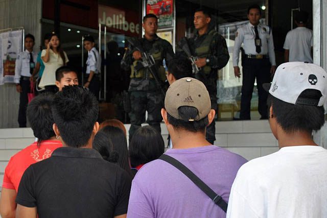 PRE-RUBY. Residents queue up while armed policemen stand guard at the entrance of a shopping mall in Tacloban City on December 4, 2014. Photo by Lito Bagunas/AFP