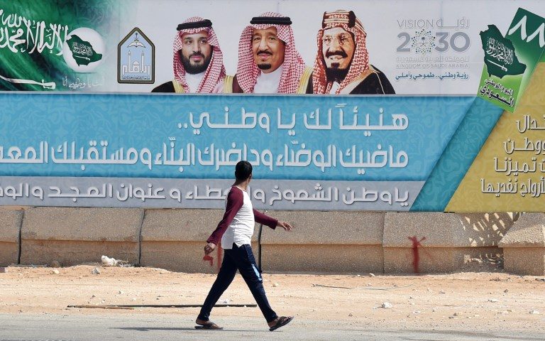 MONARCHS. A foreign laborer walks past a banner with portraits of Saudi King Salman bin Abdulazziz (C), his son Crown Prince Mohammed bin Salman (L) and the founder of the Kingdom King Abdulazziz al-Saudm on October 18, 2018 in Riyadh. Photo by Fayez Nureldine/AFP 