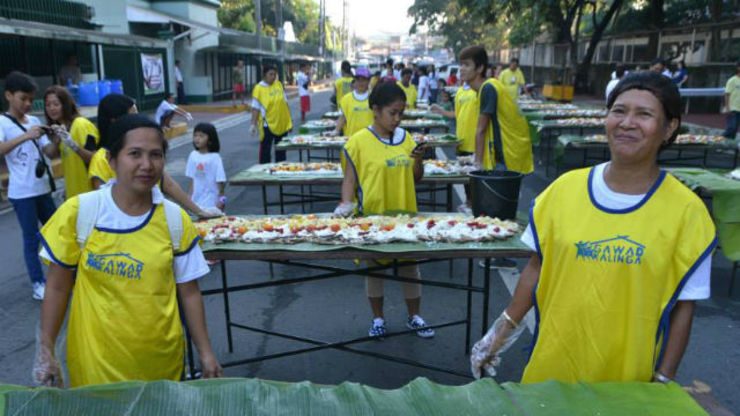 BAYANIHAN. GK volunteers help set up the big feeding program in one of the busiest streets in Quezon City. 