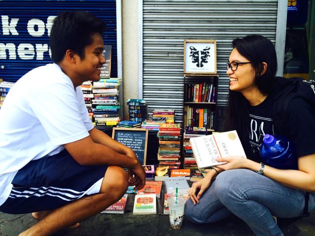RIGHT TO EDUCATION. Michaela Manahan, a University of the Philippines (UP) law student, chats with Justin Decastro after buying a book from him. “It's unfair that he has to do this. Everyone has the right to education. But it's admirable that he’s doing so much for that privilege that he’s supposed to enjoy,” she says. Photo by Voltaire Tupaz/Rappler.com
    