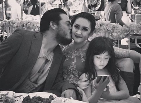 Zack Lee mengecup pipi Nafa Urbach saat sedang makan malam bersama putri mereka Mikhaela Lee Juwono. Foto dari Instagram/nafaurbach 