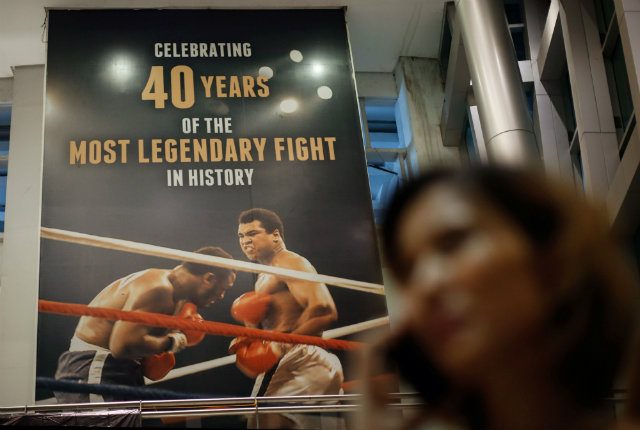 STILL THRILLED. A Filipino uses her mobile phone next to a giant poster celebrating 40 years of the heavyweight boxing bout between Muhammad Ali and Joe Frazier in 1975 dubbed 'Thrilla in Manila' at the Araneta Coliseum in Quezon City. Photo by Mark Cristino/EPA 
