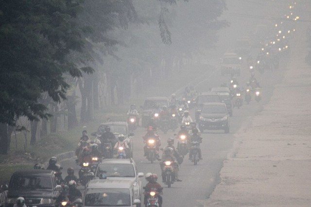 MELAWAN ASAP. Masyarakat Pekanbaru, Riau, menerjang kabut asap yang semakin tebal. Foto oleh AFP
