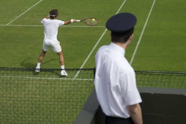A security staff member watches Roger Federer during a training session at the All England Lawn Tennis Championships in Wimbledon on Thursday, June 25. Photo by PETER KLAUNZER/EPA 