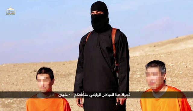 HOSTAGES.  An image grab taken off a video on January 20, 2015, reportedly released by the Islamic State (IS) group through Al-Furqan Media, one of the Jihadist platforms used by the militant organisation on the web, allegedly shows Japanese hostages Kenji Goto (L) and Haruna Yukawa (R) in orange jumpsuits with a black-clad militant brandishing a knife as he addresses the camera in English, standing between them at an undisclosed location. Photo by AL-FURQAN MEDIA/AFP