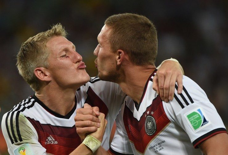 Lukas Podolski and Bastian Schweinsteiger fake a kiss for the press in celebration of their fourth World Cup title. Photo by Patrik Stollarz/AFP