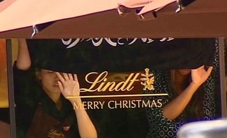 TERROR IN SYDNEY. This screengrab taken from the Australian Channel Seven broadcast shows presumed hostages holding up a flag with Arabic writing inside the Lindt cafe in the central business district of Sydney on December 15, 2014. Channel Seven/AFP